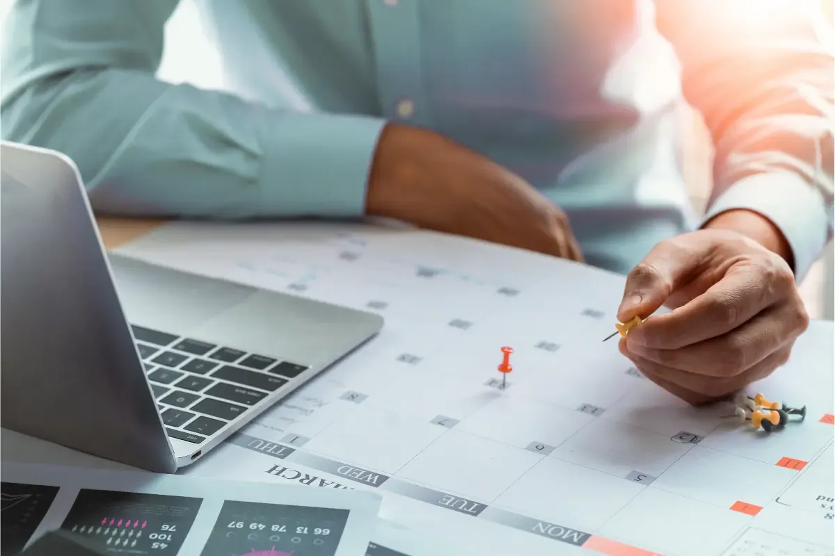 compliance-calendar-img.webp Business owner planning compliance deadlines on calendar with laptop for annual report filing and corporate compliance management.