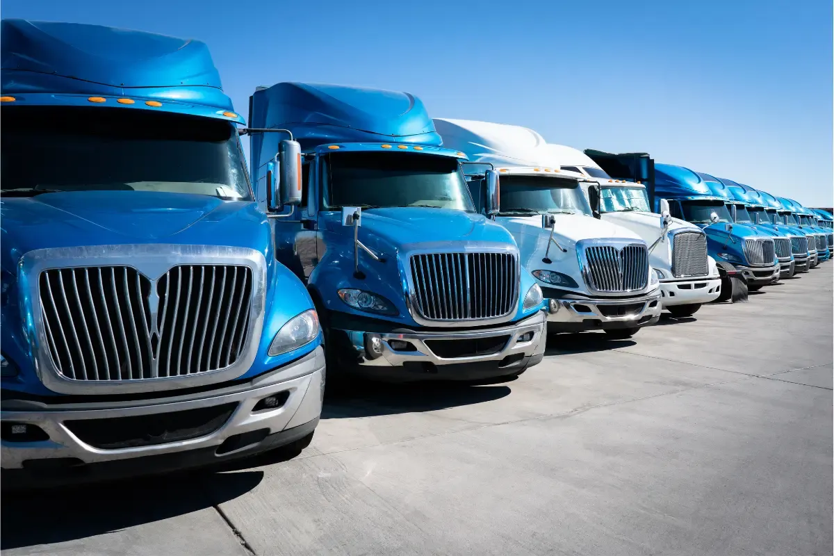 trucking-compliance-services-dot-compliance-guide-img.webp Row of commercial semi-trucks in a fleet lineup used for DOT compliance and trucking operations.